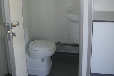 Toiletrum med kemisk toilet og håndvask med koldt og varmt vand samt radiatorvarme.